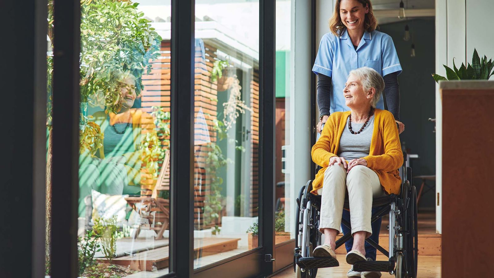 nurse pushing elder woman in wheelchair